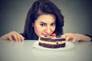 woman with cravings staring intensely at piece of chocolate cake
